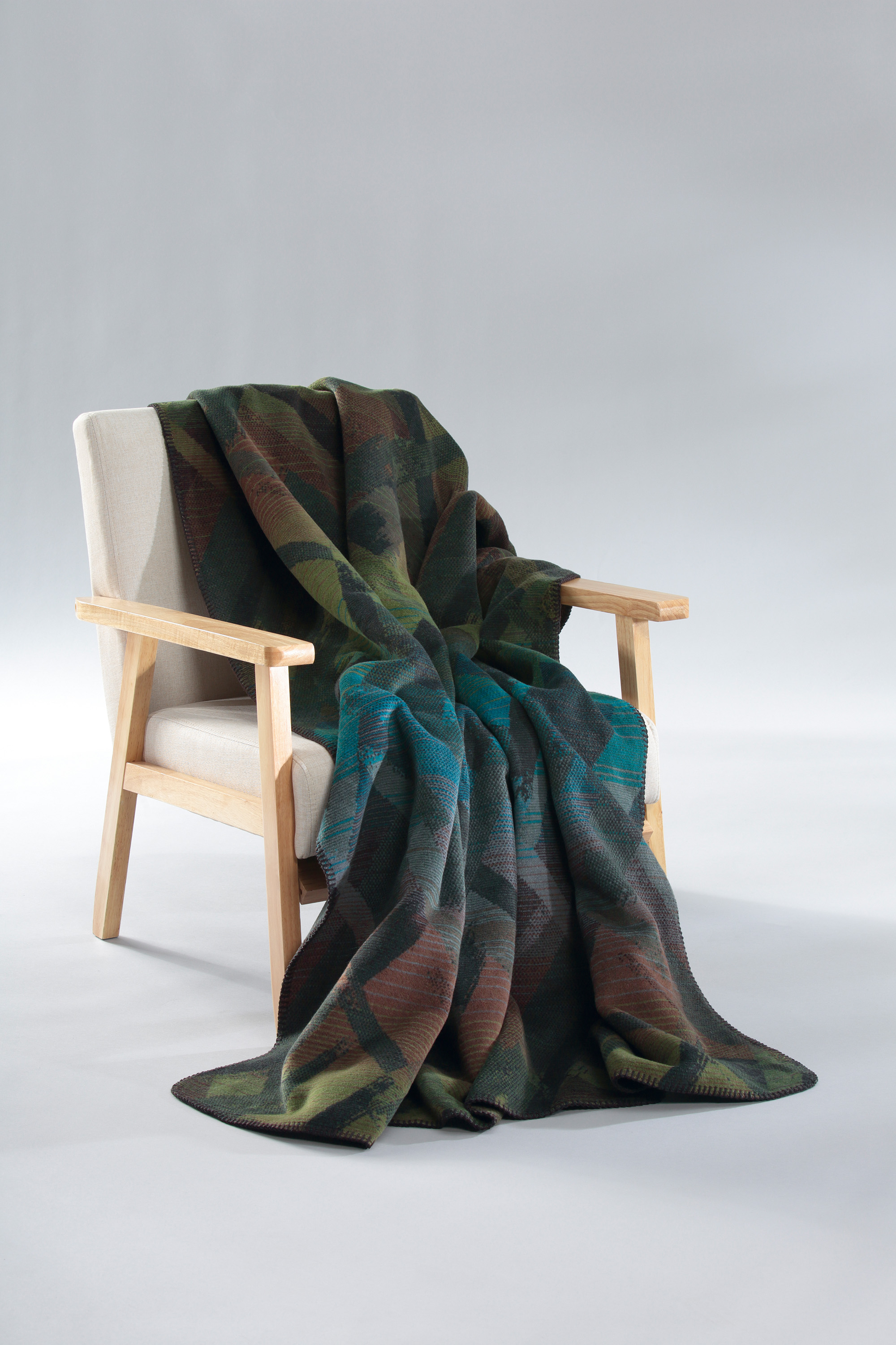 Kuscheldecke Mossy Glow auf Sessel gelegt