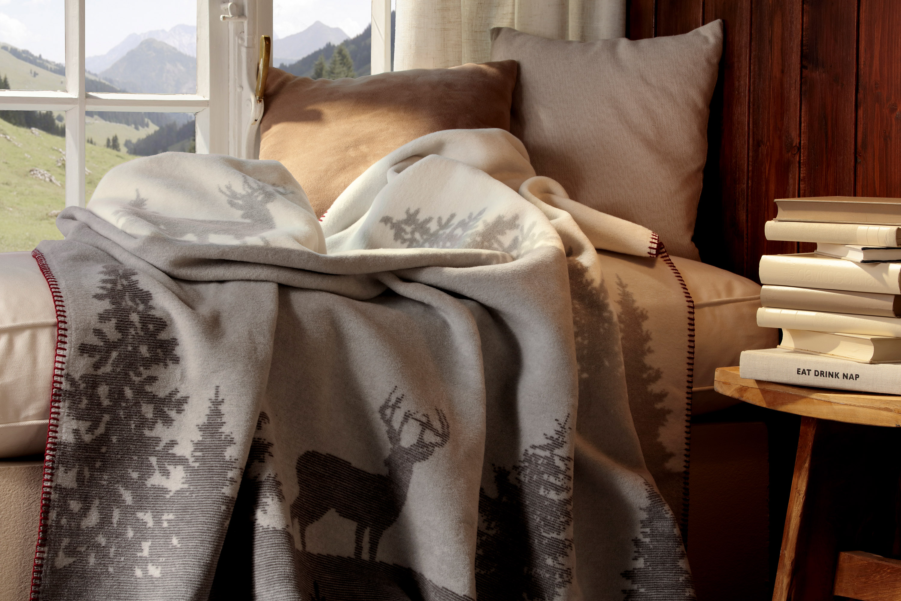 Wohndecke Deerlight auf Sofa liegend vor einem Fenster