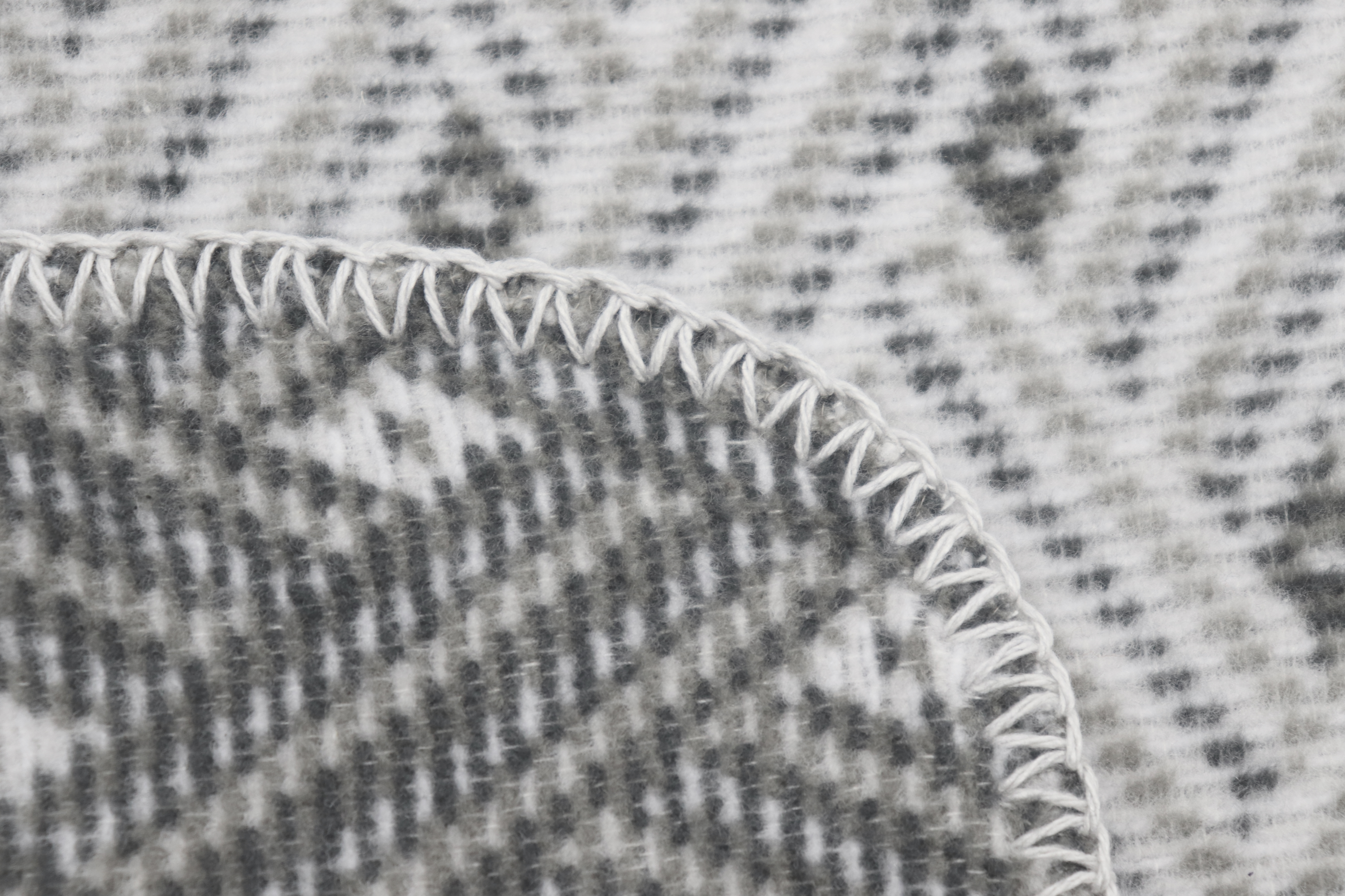 grau gemusterte Kuscheldecke "Network" aus Baumwollmischgewebe - Detailaufnahme Zierstich