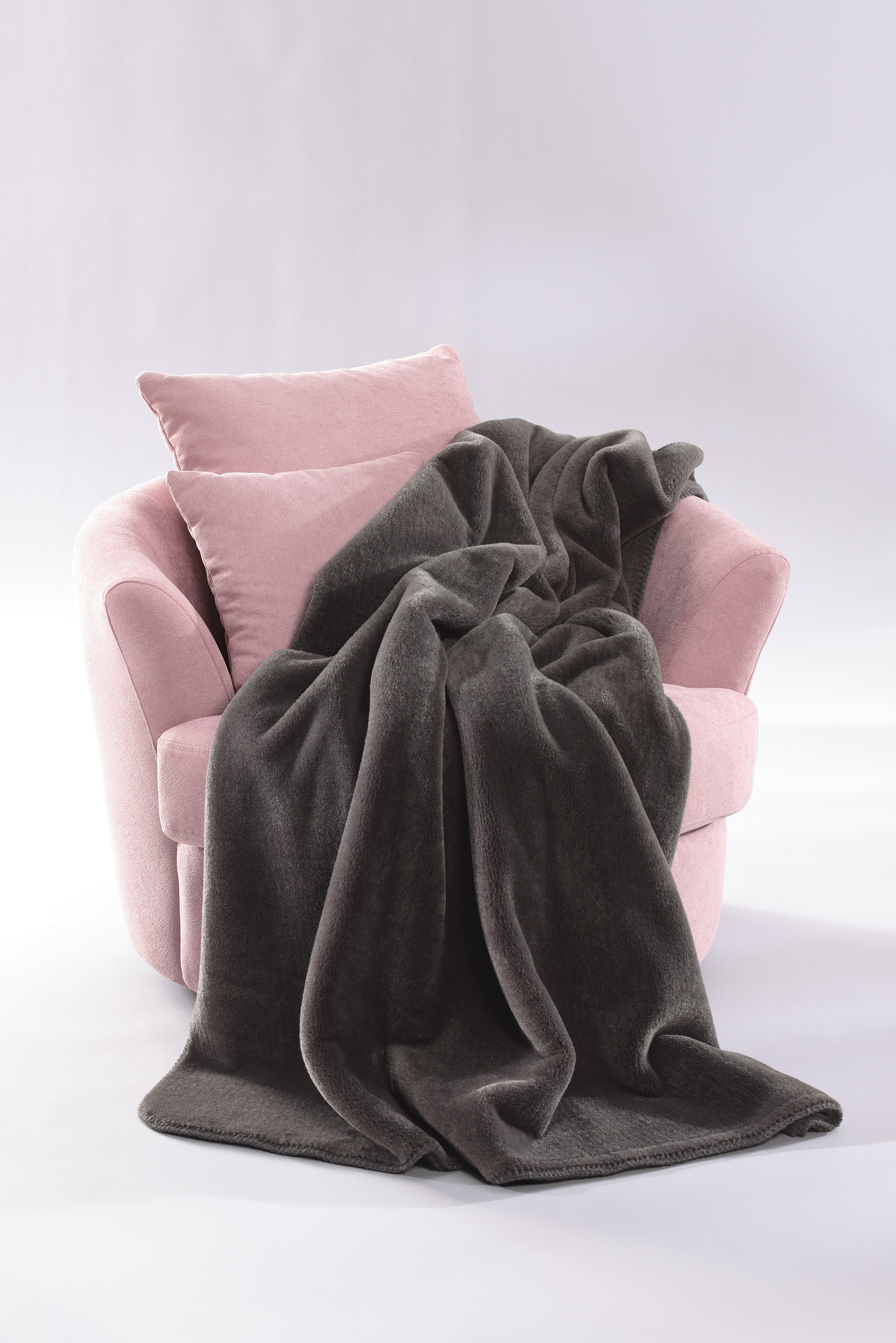 Wohndecke Wool Feel grey auf Sessel gelegt