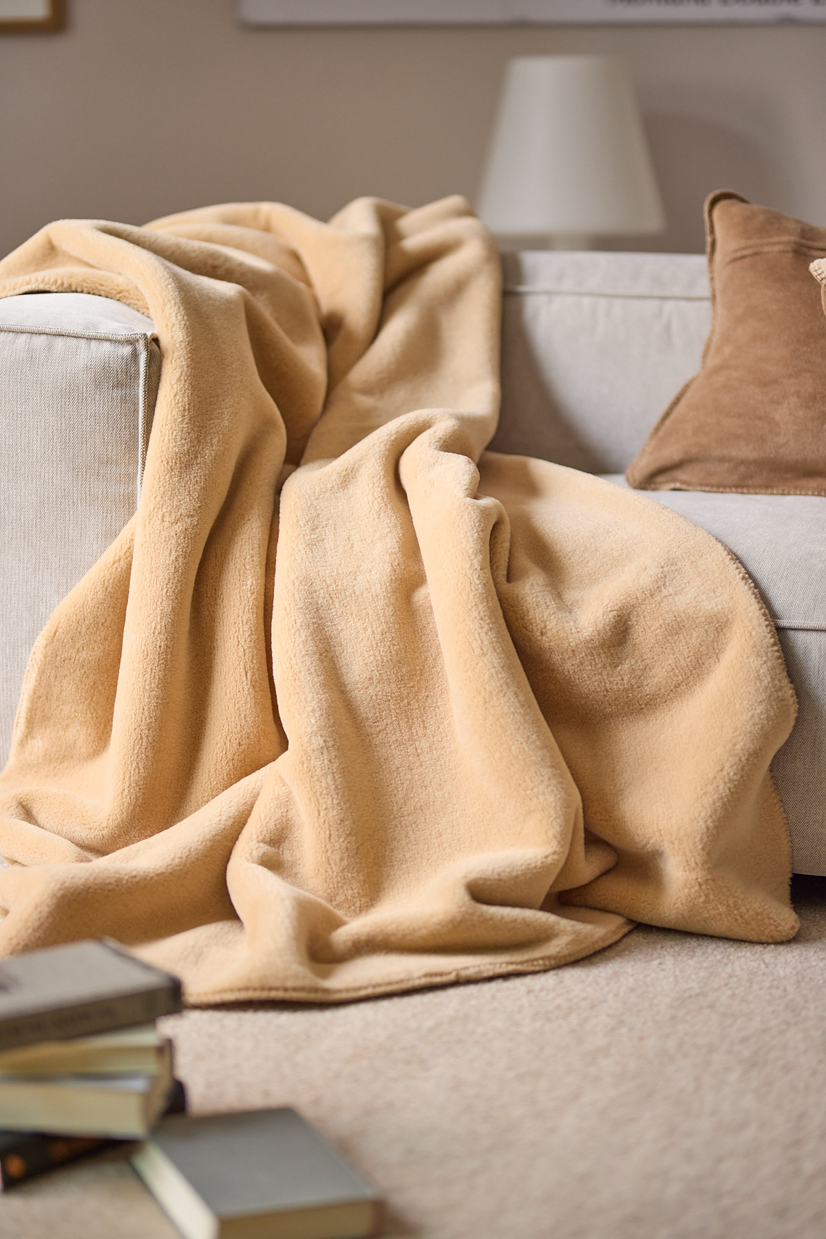 Kuscheldecke Wool Feel camel Milieubild auf Couch