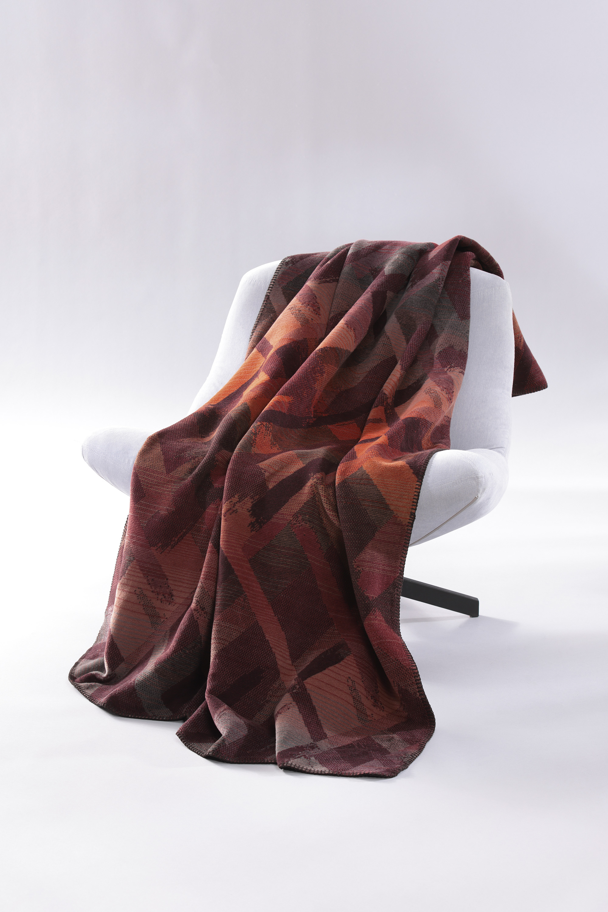 Kuscheldecke Garnet Glow auf Sessel gelegt